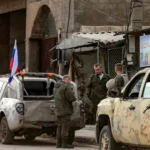 Российские солдаты стоят у военных пикапов