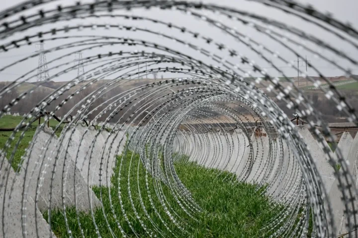 Колючая проволока в форме спирали и противотанковые сваи