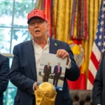 Президент Дональд Трамп держит фотографию